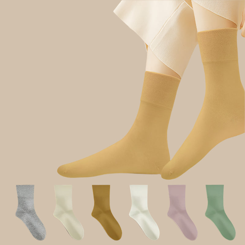 A model wearing cream crew socks with white pants, shown above a collection of six different colored socks in gray, ivory, camel, white, lilac, and sage green