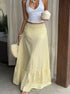 Woman wearing yellow ruffle midi skirt with white crop top and coconut in hand