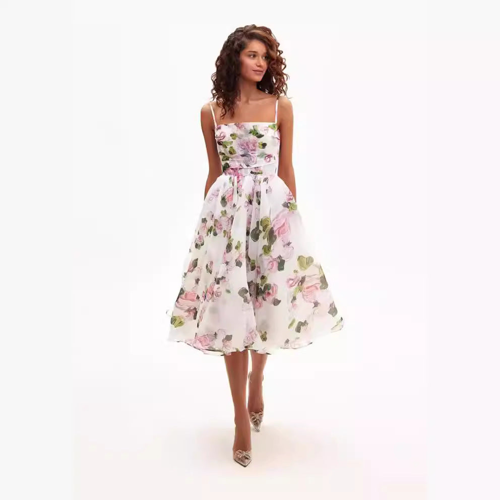 A model is wearing a white midi dress with pink rose print and spaghetti straps, featuring a full A-line skirt against a white background