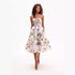 A model is wearing a white midi dress with pink rose print and spaghetti straps, featuring a full A-line skirt against a white background