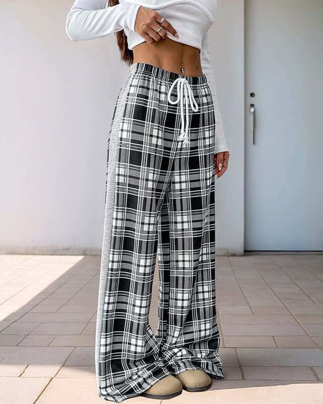 High-waisted black and white plaid wide-leg pants with a drawstring waist, paired with a white crop top and beige sneakers.