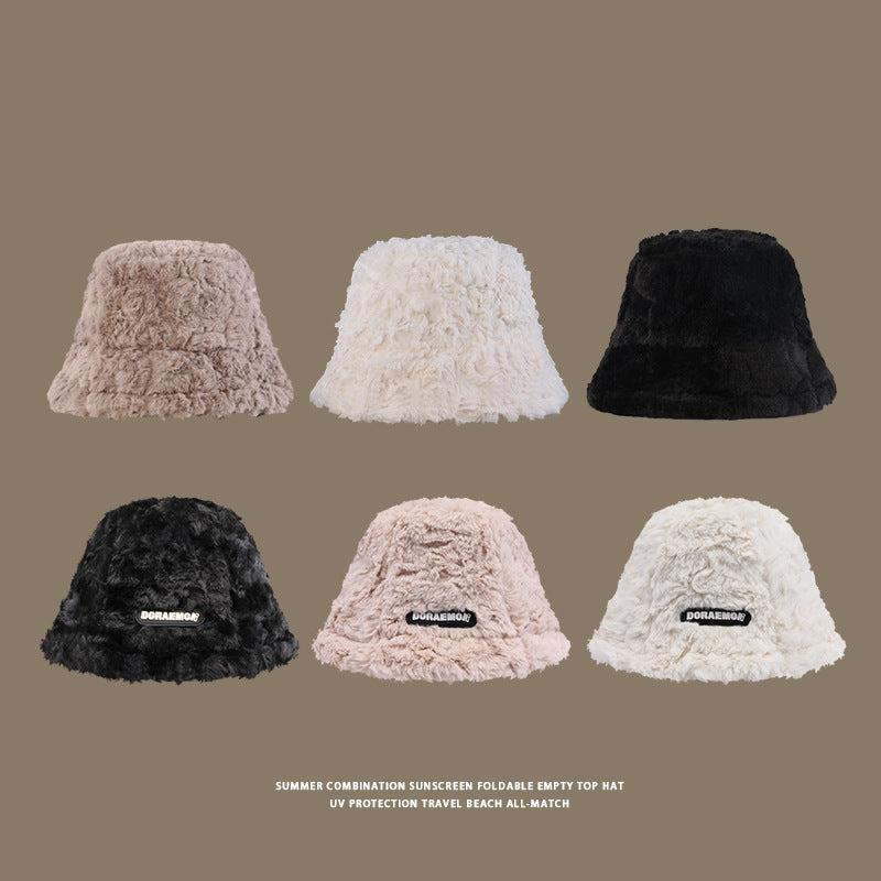 Six plush faux fur bucket hats in beige, white, and black displayed on a neutral background, some featuring a logo patch