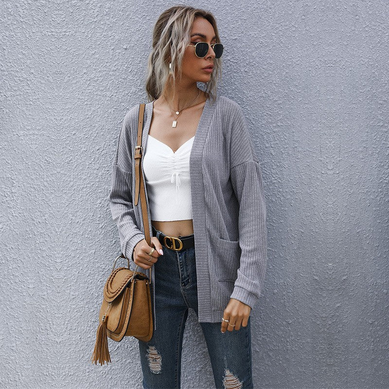 Chic street style outfit with grey ribbed cardigan, white crop top, distressed jeans, sunglasses