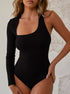 Woman wearing a black one-shoulder bodysuit with long sleeve, posing against a neutral backdrop.