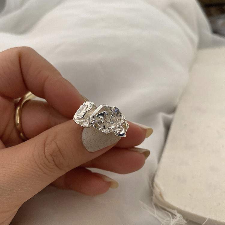 Close-up of sterling silver statement ring with unique crumpled paper texture design against white background