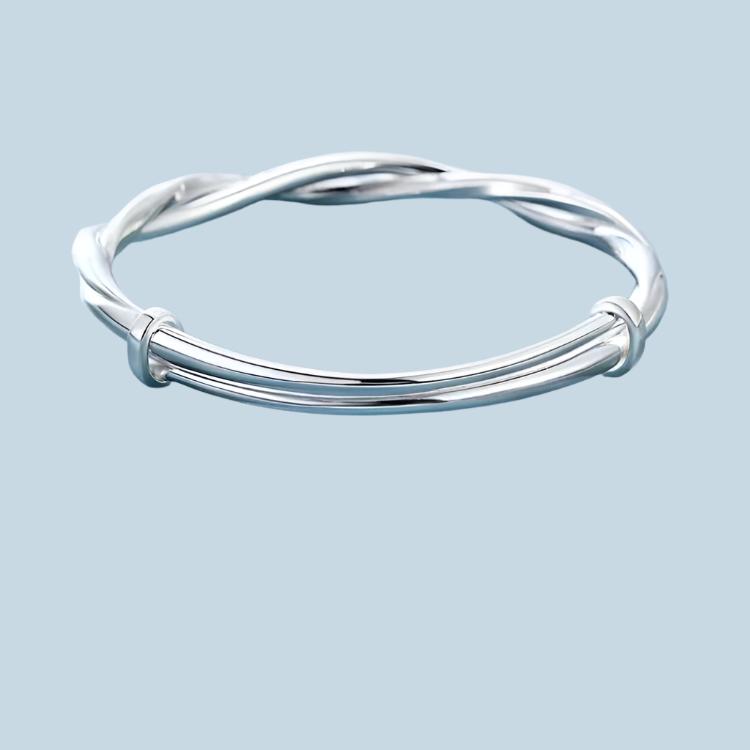 A silver twisted wire bangle bracelet with polished finish displayed against a light blue background