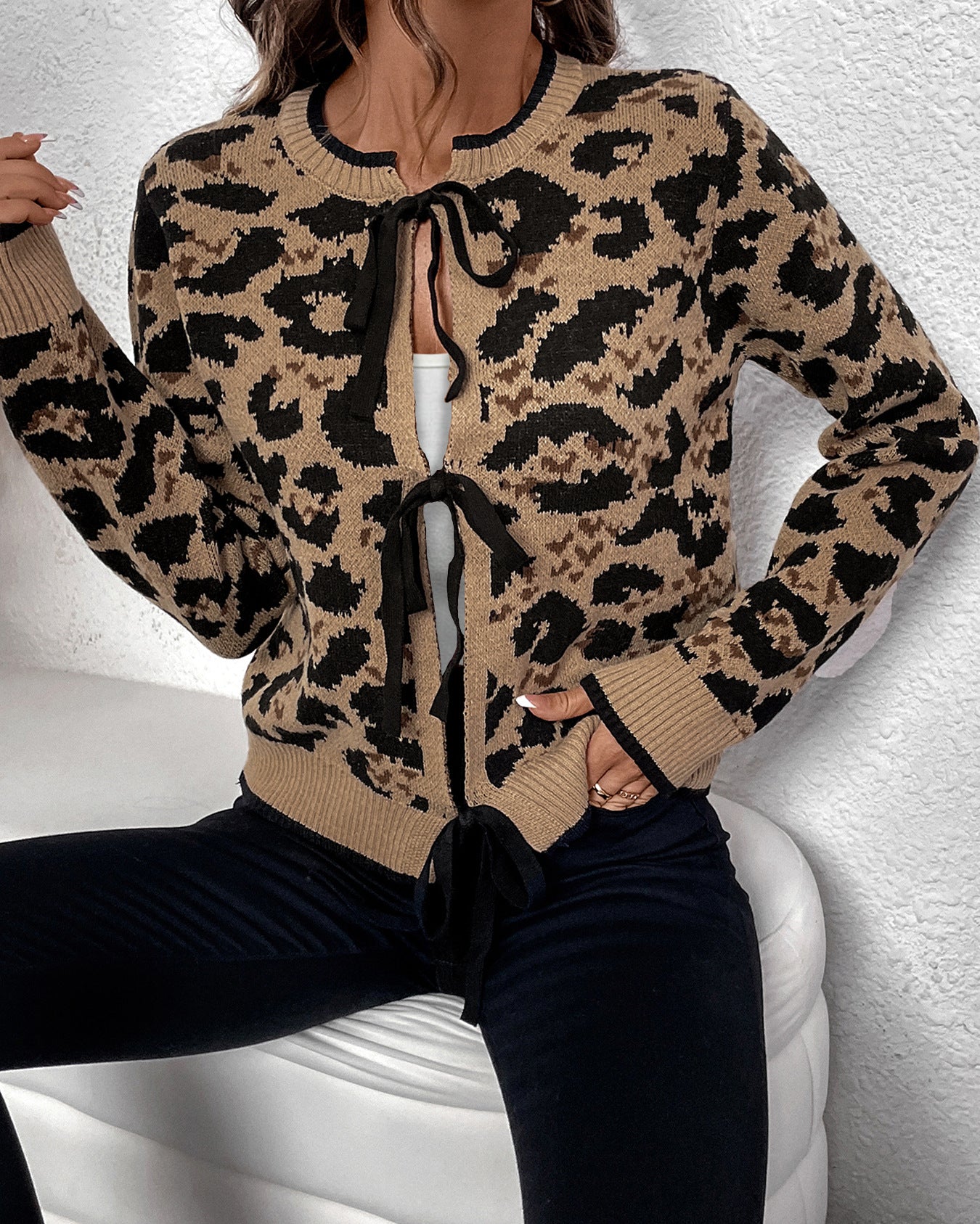Model wearing tan and black leopard print cardigan with front tie closure and ribbed trim, styled with black pants