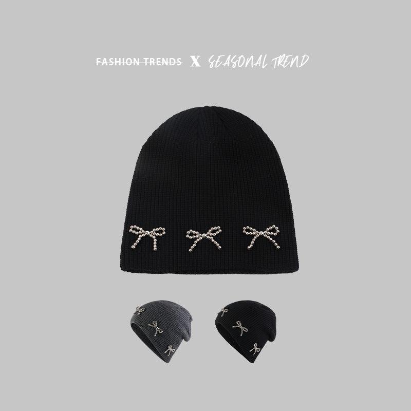 Black knit beanie with three pearl-studded bow decorations, displayed with text "Fashion Trends X Seasonal Trend" and showing two color variations