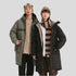 A man and woman wearing NEIGHBORHOOD parkas stand together against white background, modeling green and black outerwear with winter accessories