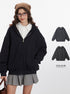 A model wears a black oversized hoodie over a white shirt and gray skirt. Two hoodie color variations are displayed on the right