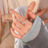 Hand wearing a silver butterfly ring with sparkling stones, holding a phone in a cozy setting