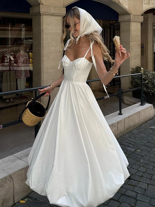 Woman in a white dress with a headscarf walking outdoors.