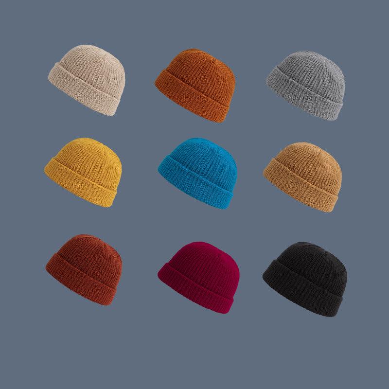 A grid display of nine ribbed knit beanies in various colors including beige, orange, gray, yellow, blue, brown, rust, burgundy, and black against slate background
