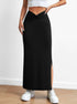 Black long skirt with side slit and twisted waistband, paired with white sneakers and a white cropped top, photographed against a light background