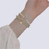 Delicate bracelet combination featuring light green jade beads and white pearl beads with a gold-toned charm, worn on a wrist with a white textured sleeve