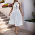 Woman wearing a white polka dot halter dress with ruffle detailing and cutout front, walking outdoors with a relaxed fit.