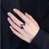 Black lightning bolt ring worn on pale hand against dark fabric background