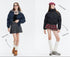 Two women pose in puffer jackets; one in navy with a gray skirt, the other in black with a red plaid skirt, against a white background
