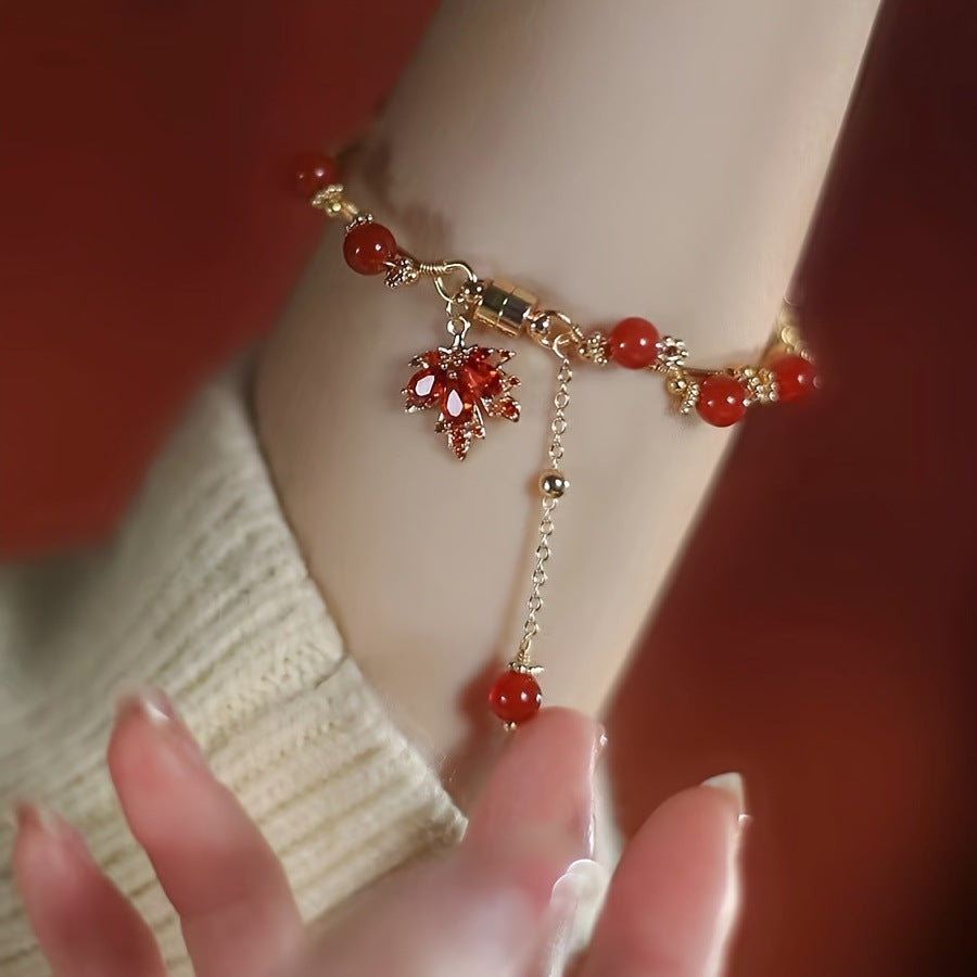 Elegant red agate bracelet with maple leaf charm and gold-tone details