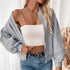 Gray bomber jacket with white crop top, model wearing gold chain necklace and jeans