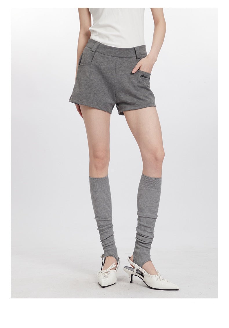 Woman wearing gray cotton shorts with pockets, styled with white tee and gray knee socks with vintage heels