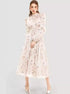 Woman wearing a vintage-inspired long-sleeve floral maxi dress with a high neckline, cinched waist, and delicate ruffle details, paired with silver heels