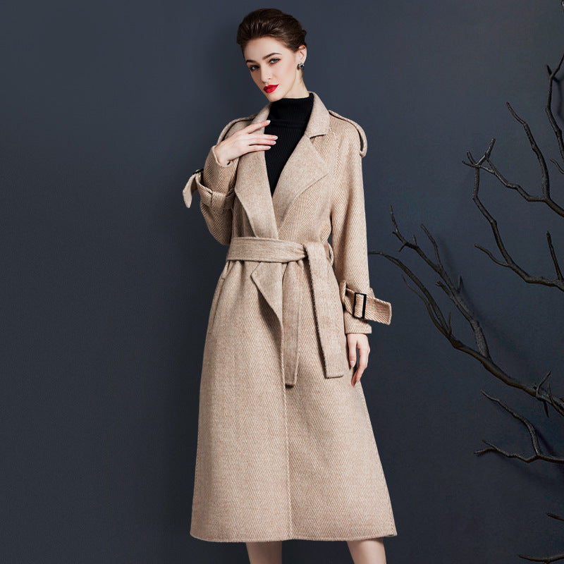 Woman in a beige wool trench coat with a belted waist, wearing a black turtleneck