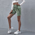 Model poses in high-waisted green tie-dye biker shorts paired with a white long-sleeve cropped top and chunky white sneakers