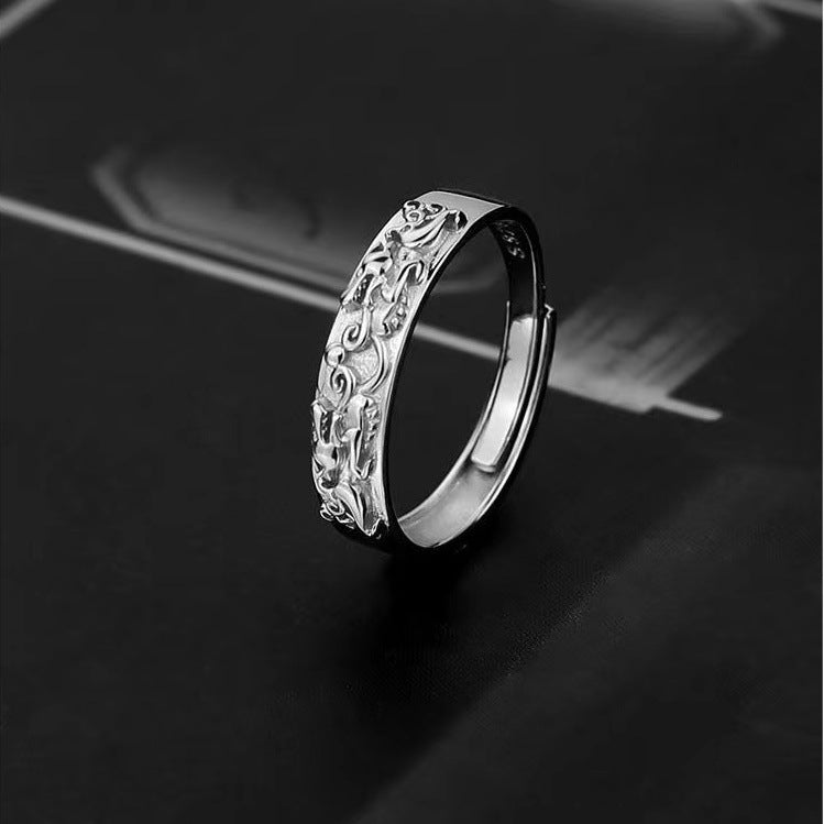 Silver band ring with intricate scroll and floral engraved pattern on dark background showcasing vintage-inspired design