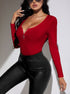 Woman in a red ribbed long-sleeve bodysuit with a front zipper, paired with black leather pants, accessorized with sunglasses and rings.