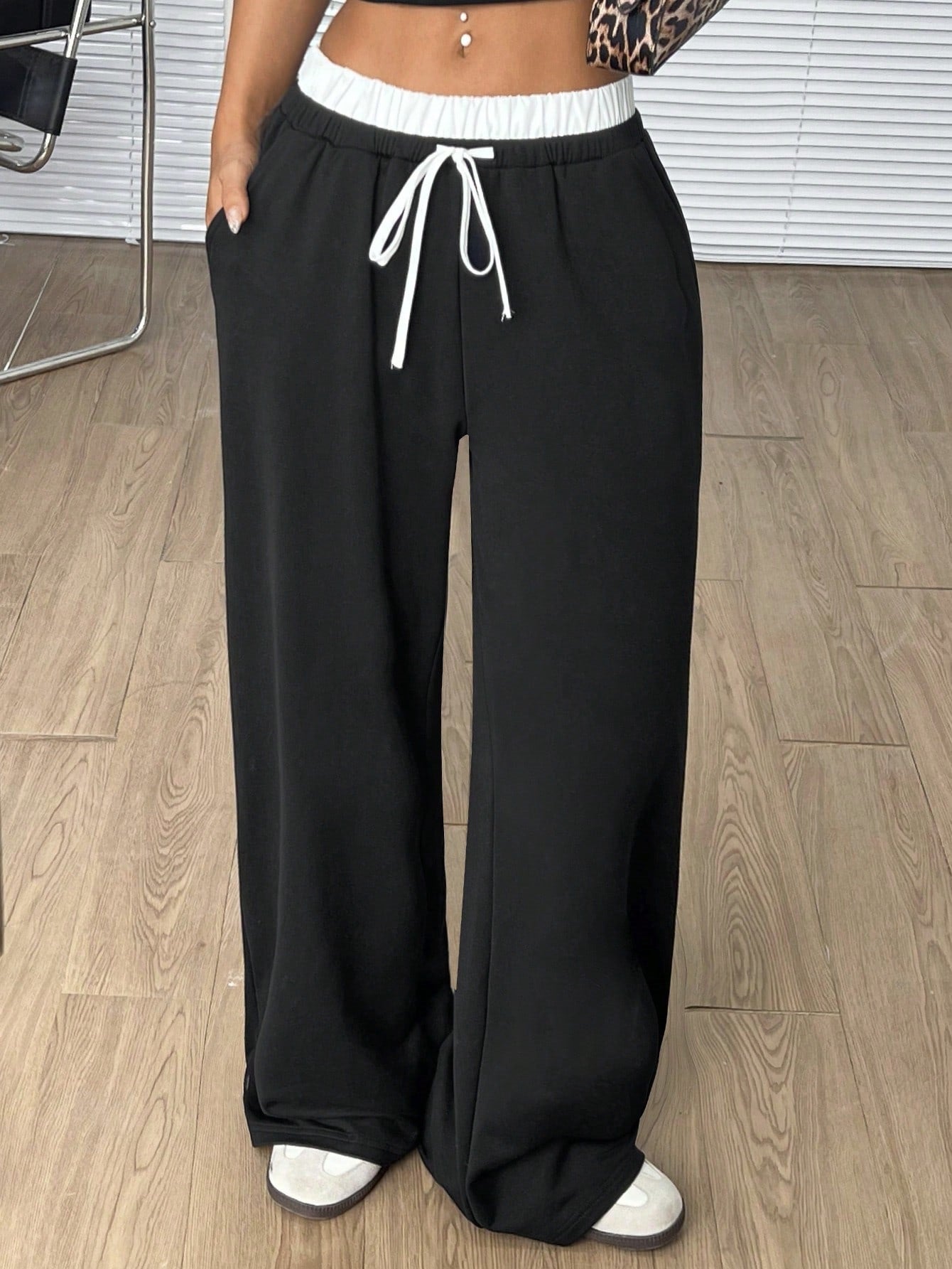 Black wide-leg pants with white elastic waistband and drawstring, styled with white sneakers