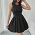 A woman in a sleeveless black fit-and-flare dress with a ruched bodice and a voluminous bubble hem, accessorized with a silver bracelet and necklace.