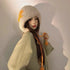 Young woman wearing cream furry winter hat with orange lightning bolt design and matching orange braided ties