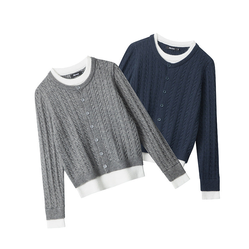 Cable knit cardigans in grey and navy, featuring white contrast trim at neckline, cuffs, and hem. Button-front closure and all-over cable pattern.