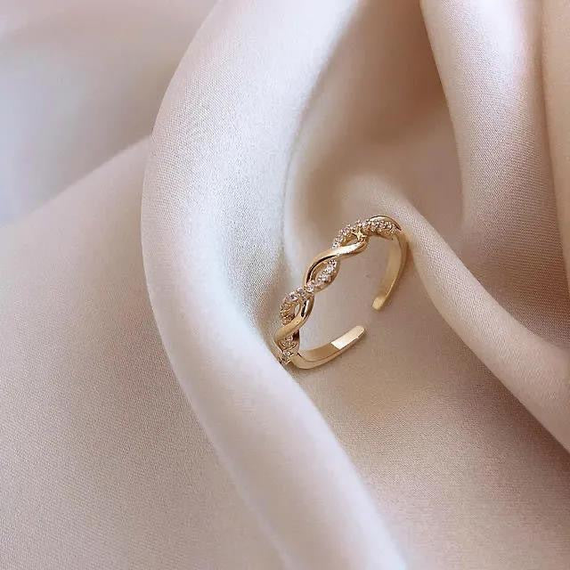Gold twisted band ring with crystal accents displayed on cream silk fabric
