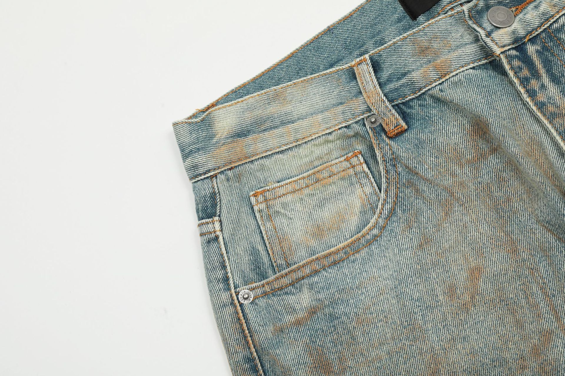 Close-up detail of light wash denim showing pocket construction and faded texture against white background