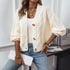 Off-white cable knit cardigan with decorative buttons, styled with multiple gold chain necklaces