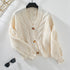 Ivory knit cardigan hanging on black hanger, showcasing textured fabric and design details