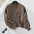 Taupe cable knit cardigan with tortoiseshell buttons, laying flat with minimalist styling