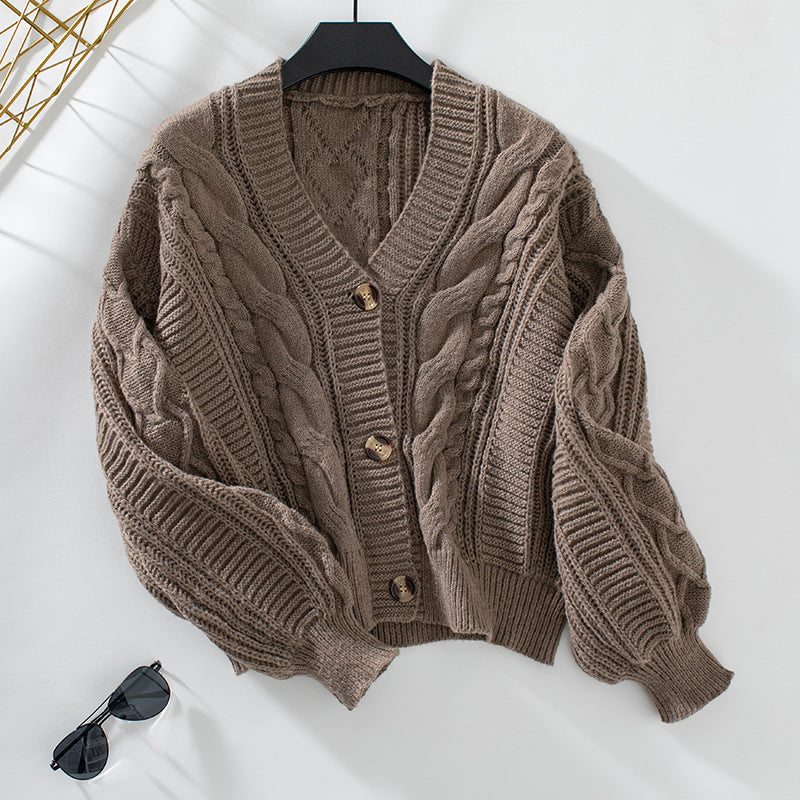 Taupe cable knit cardigan with tortoiseshell buttons, laying flat with minimalist styling