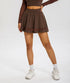 Brown athletic skirt with high waistband and mesh panel trim detail, paired with coordinating long sleeve crop top