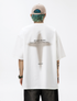 A man is standing with back to camera against white backdrop. Wearing white tee with cross graphic and "HEADSTRONG" text, beige cap and blue-green hair