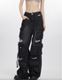 A model wearing grey crop top and black distressed cargo pants with multiple pockets, standing against white background