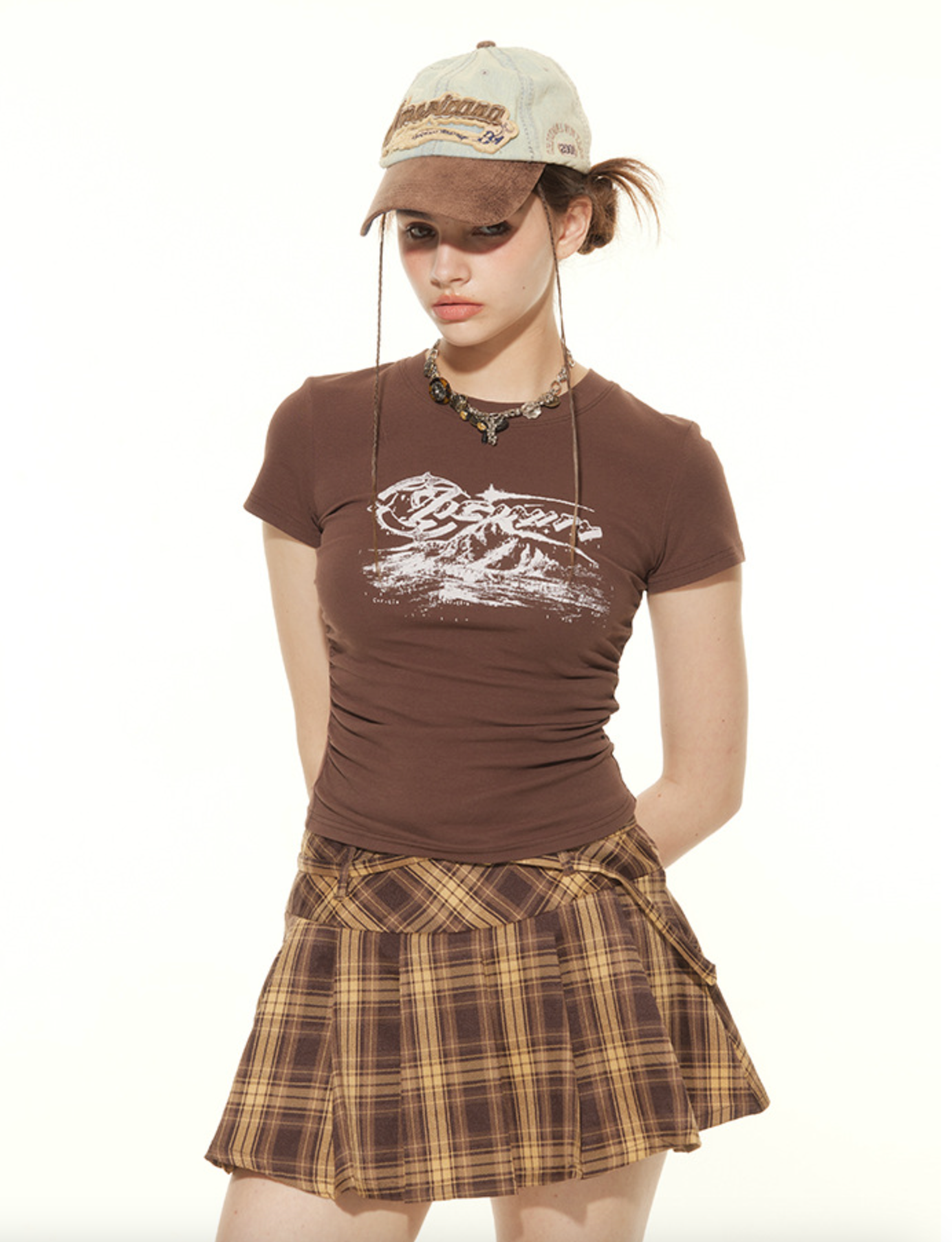 Close-up of retro mountain print t-shirt with plaid mini skirt and vintage accessories