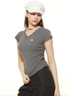 Model wearing ruched gray t-shirt with logo detail, black pants and white cap, showing streetwear styling details
