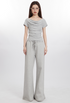 Full-body shot of model in light gray draped top and wide-leg pants, wearing glasses