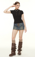 Fashion model posing in black mock neck tee and denim mini, showcasing Y2K inspired styling with statement boot