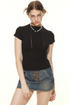 Model wearing fitted black tee and lace-up denim skirt, styled with vintage accessories and statement pose