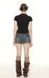 Back view of model in black tee and distressed denim mini skirt, showcasing casual Y2K streetwear style with boots