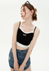 A woman is posing with head turned, wearing a black crop top with white trim detail, distressed denim mini skirt and sunglasses on her head